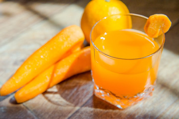 Carrot juice. Healthy food, healthy drink. Orange juice in a glass and next to peeled carrots, sliced cucumber. healthy eating for breakfast. Wood background
