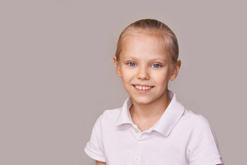 Young beauty girl portrait. Look at camera. Neutral background. Female teenager after study classroom. Little woman portrait. Smile with teeth. Copyspace. Horizontal