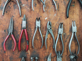 Mechanics tools for repairing an fixing organized on wooden panel board consisted of different sets of pliers in a workshop