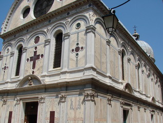 Bottom view of the architectural grandeur of the amazing beauty of the sculptural compositions of Venetian temples and cathedrals in the middle of a summer sunny day.