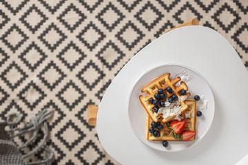 Beautiful breakfast: Viennese Belgian waffles decorated with berries, a plate with strawberries and blueberries