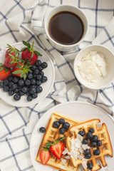 Beautiful breakfast: Viennese Belgian waffles decorated with berries, a plate with strawberries and blueberries