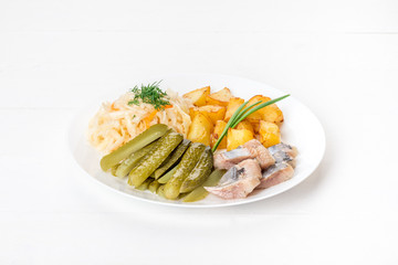 In a white plate, pickles, cabbage, potatoes, fish.