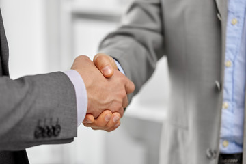 business people, cooperation, partnership and deal concept - close up of businessmen making handshake at office