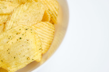 Fluted chips with spices in a white plate on a white background.