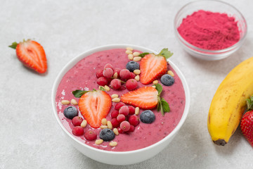 Healthy breakfast bowl: berry smoothie with banana, strawberries, blueberries, red currants, granola and acai berry powder.