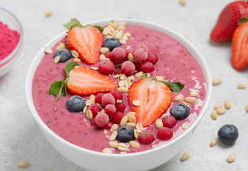 Healthy breakfast bowl: berry smoothie with banana, strawberries, blueberries, red currants, granola and acai berry powder.