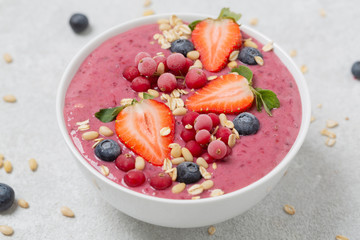 Healthy breakfast bowl: berry smoothie with banana, strawberries, blueberries, red currants, granola and acai berry powder.