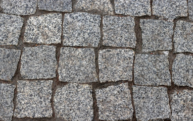 Granite cobblestoned pavement background. Cobbled stone road regular shapes, abstract background of old cobblestone pavement close-up