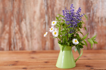 gardening, plants and organic concept - bunch of herbs and flowers in green jug on table