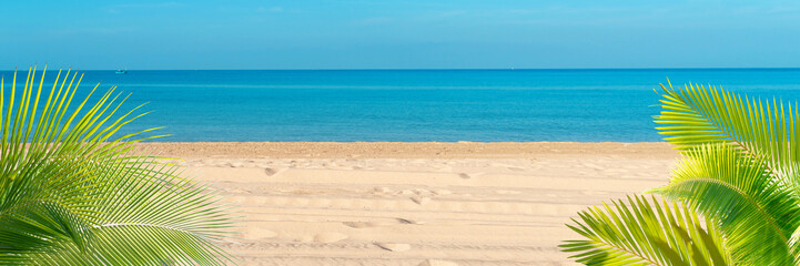 Fototapeta na wymiar Tropical sea beach with sand, ocean, palm leaves and blue sky