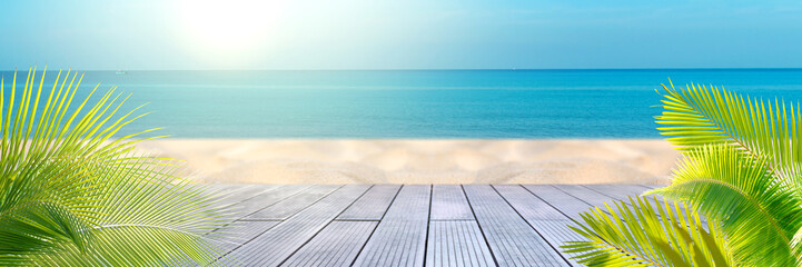 Tropical sea beach with sand, ocean, palm leaves and blue sky