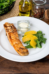 In a white plate, a piece of fried fish with sauce and lemon.