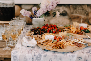 the buffet at the reception. Glasses of wine and champagne. Assortment of canapes on wooden board. Banquet service. catering food, snacks with cheese, jamon, prosciutto and fruit