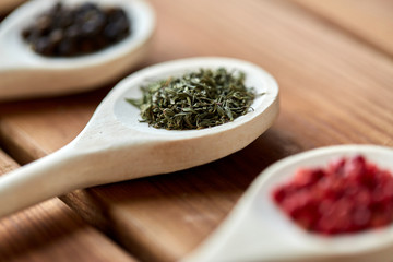 food, culinary and unhealthy eating concept - spoons with different spices on wooden table