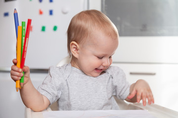 Cute baby paint using colorful pencils on white table