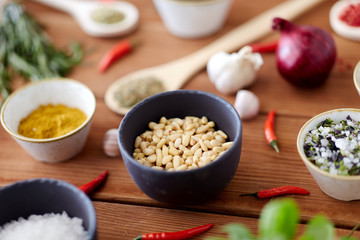 food, culinary and eating concept - pine nuts in bowl and spices on wooden kitchen table