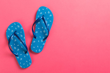 Blue flip flops on pink background. Top view with copy space