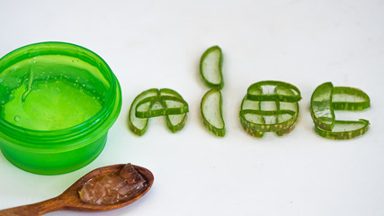Green jar with wooden spoon and Aloe vera Cut into pieces, Placed in the letters 