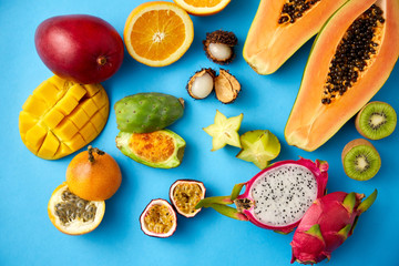 food, summer and healthy eating concept - different exotic fruits on blue background