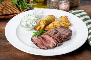 In a white plate steak with pancakes and sauce