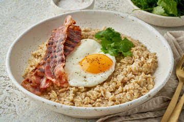 Oatmeal, fried egg, fried bacon. Hearty fat high-calorie breakfast. Balance of proteins, fats, carbohydrates, side view