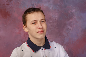 a young man in a white t-shirt with a blue collar, taken by the light of a softbox against a multicolored wall