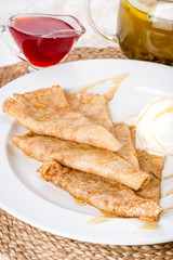 On a white plate are pancakes with creamy ice cream.