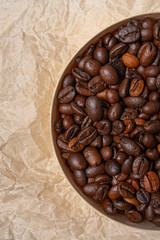 coffee grains in a round wooden jar on a background of crumpled parchment