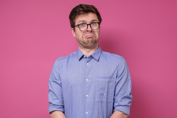 Sad young caucasian man in glasses looking bored is about to cry.