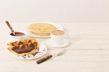 pancakes with chocolate and coffee on white wooden background