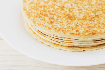 pancakes on plate on white wooden background