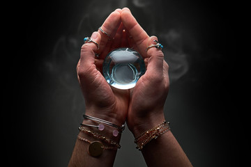 Magic blue crystal ball with smoke in hands of fortune teller for prediction and divination on a...