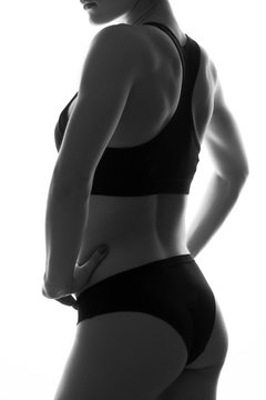 Sexy slim fit woman body with dumbbells. Muscled abdomen. Sportswear. Isolated on white. Black and white image