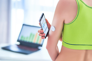 Woman diabetics control and checking glucose level with a remote sensor and mobile phone. Online...