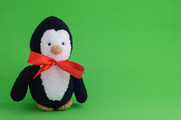 Knitted toy penguin on a green background