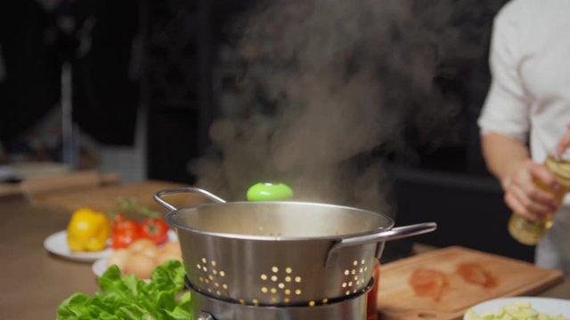 Unrecognizable Chef Pouring Olive Oil On Freshly Boiled Pasta And Tossing Pasta In Colander To Mix With Oil