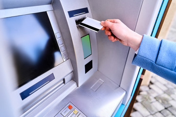 Person insert plastic credit card into street atm bank to withdrawing money - obrazy, fototapety, plakaty