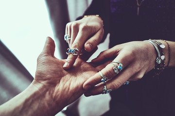 Fortune teller woman wearing silver rings with turquoise stone and bracelets reads palm lines...
