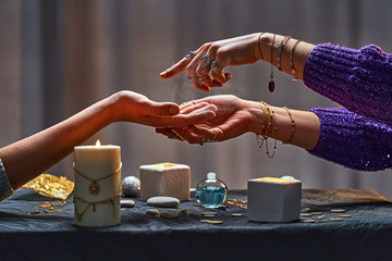 Magic gypsy woman reading palm lines around candles and other magical accessories. Witch during...