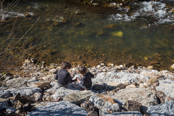 two little kids playing next to a river in Palencia, Spain, during the winter ending and the spring beginning in a warm sunny day
