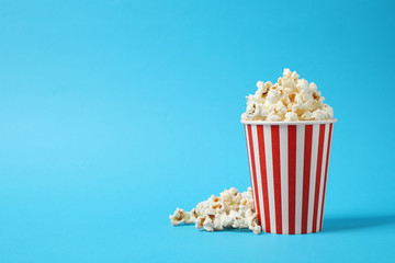 Delicious popcorn on light blue background. Space for text - obrazy, fototapety, plakaty
