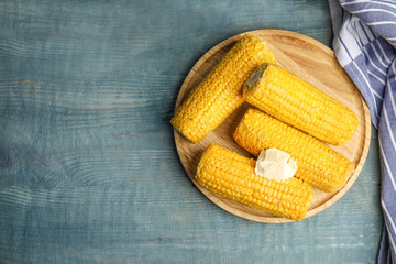 Delicious boiled corn with butter on light blue wooden table, flat lay. Space for text