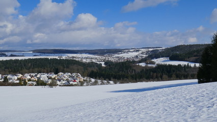 weiter Blick über sonnige Winterlandschaft mit Schnee, Wald und Dörfern im Schwarzwald
