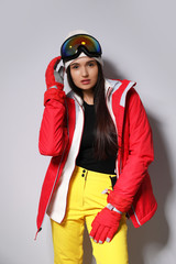 Woman wearing stylish winter sport clothes on light grey background