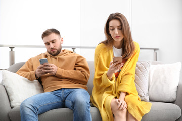 Couple addicted to smartphones ignoring each other at home. Relationship problems