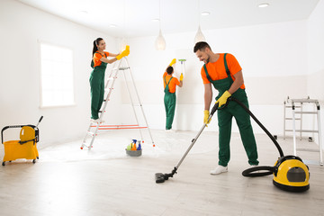 Team of professional janitors cleaning room after renovation