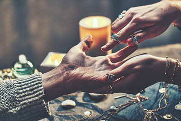 Fortune teller woman wearing silver rings with turquoise stone and bracelets reads palm lines...