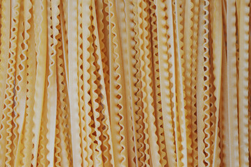 Yellow long spaghetti.Thin pasta arranged in rows. Yellow Italian pasta. Long spaghetti. Raw spaghetti wallpaper. Thin spaghetti. Food concept.