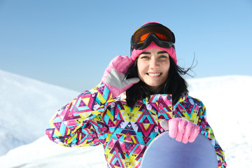 Happy young woman with snowboard in mountains. Winter vacation